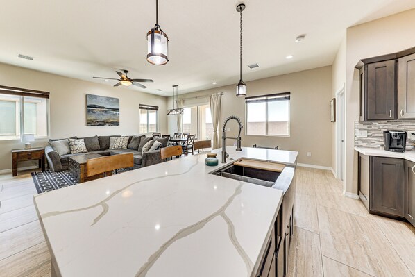 A spacious living area with a large island, dark wood cabinets, and a modern kitchen. - 3 Mi to Colorado River: New-build Family Home! (Mohave Valley)