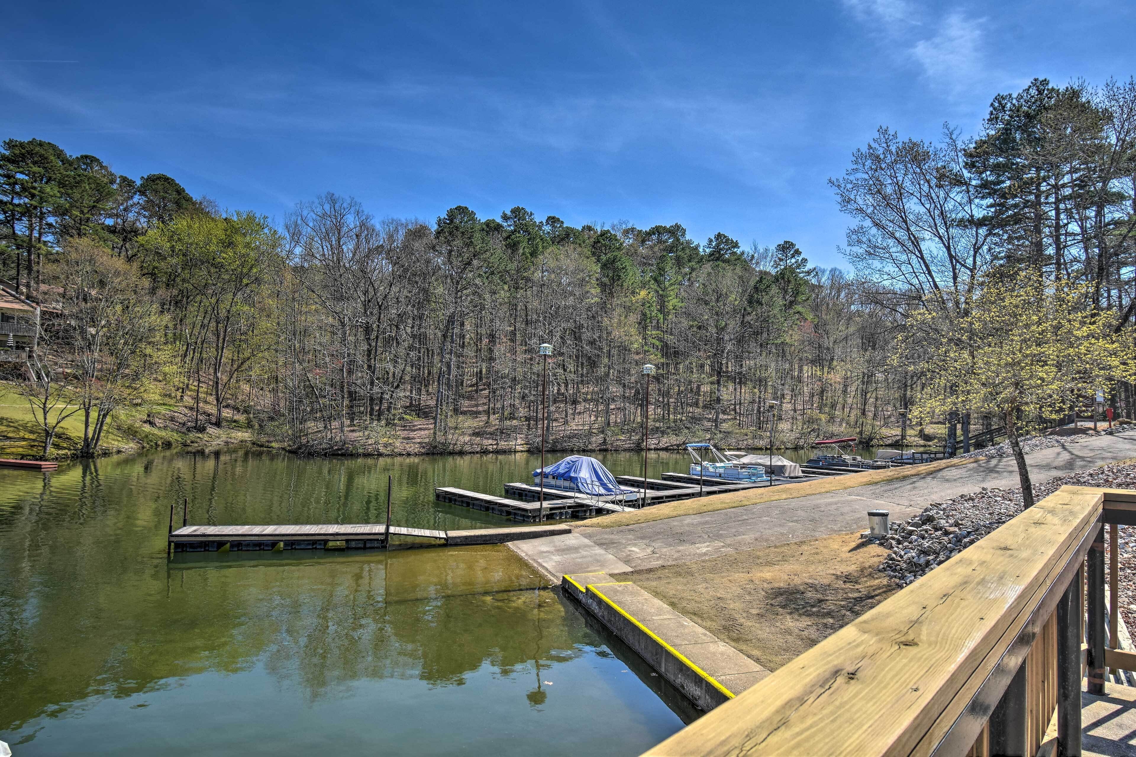 A lakeside dock with a covered boat, a wooden walkway, and a forested backdrop.