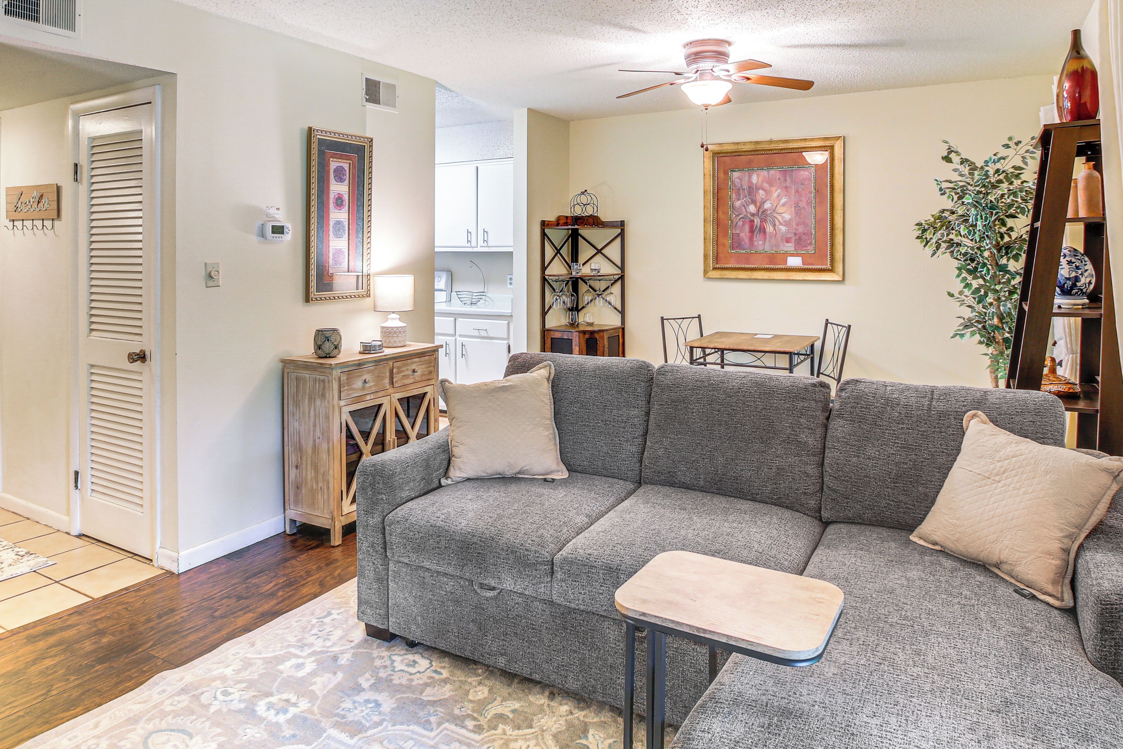 A living room with a gray sectional sofa, a small wooden table, and a ceiling fan.