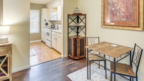 A dining area with a wooden table and chairs, a decorative metal shelf with glassware, and a framed artwork on the wall. - Walk to Lake Desoto: Home w/ Hot Tub Access! (Hot Springs Village)