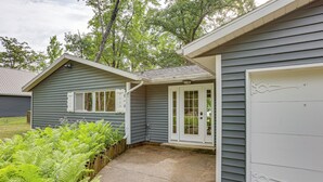 Ett hus med ett garage, en ytterdörr och en liten veranda.