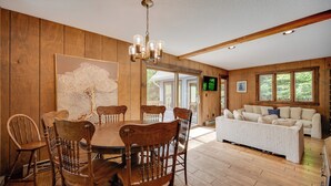 A dining area with a wooden table and chairs, a chandelier, and a large abstract painting on the wall. - White Mountain Retreat! 3 Mi to Cannon Mountain (Franconia)