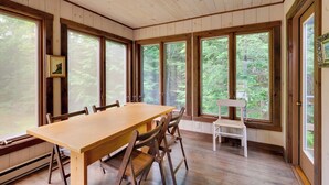 A wooden-paneled room with a large table and chairs, large windows with a forest view, and a bench by the window. - White Mountain Retreat! 3 Mi to Cannon Mountain (Franconia)