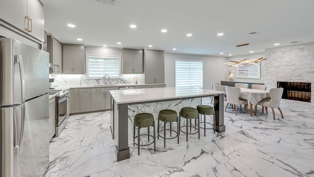 A modern kitchen with a marble countertop, stainless steel appliances, and a bar area with stools. - < 1 Mi to Sau: Newly Renovated Home w/ Yard! (Magnolia)