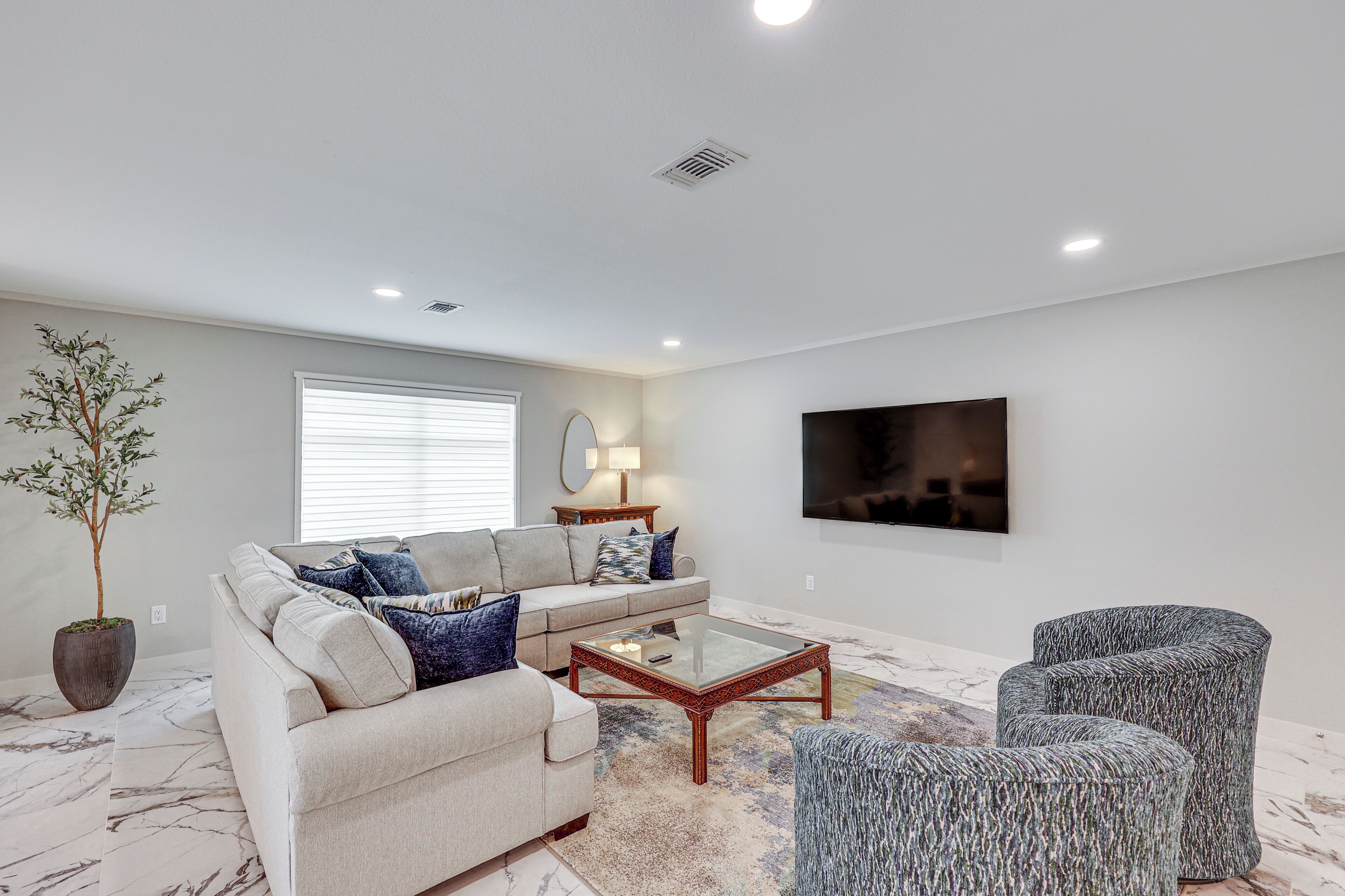 A modern living room with a sofa, coffee table, and armchairs.