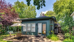 A small, single-story house with a covered patio area, a swing set, and a small garden.