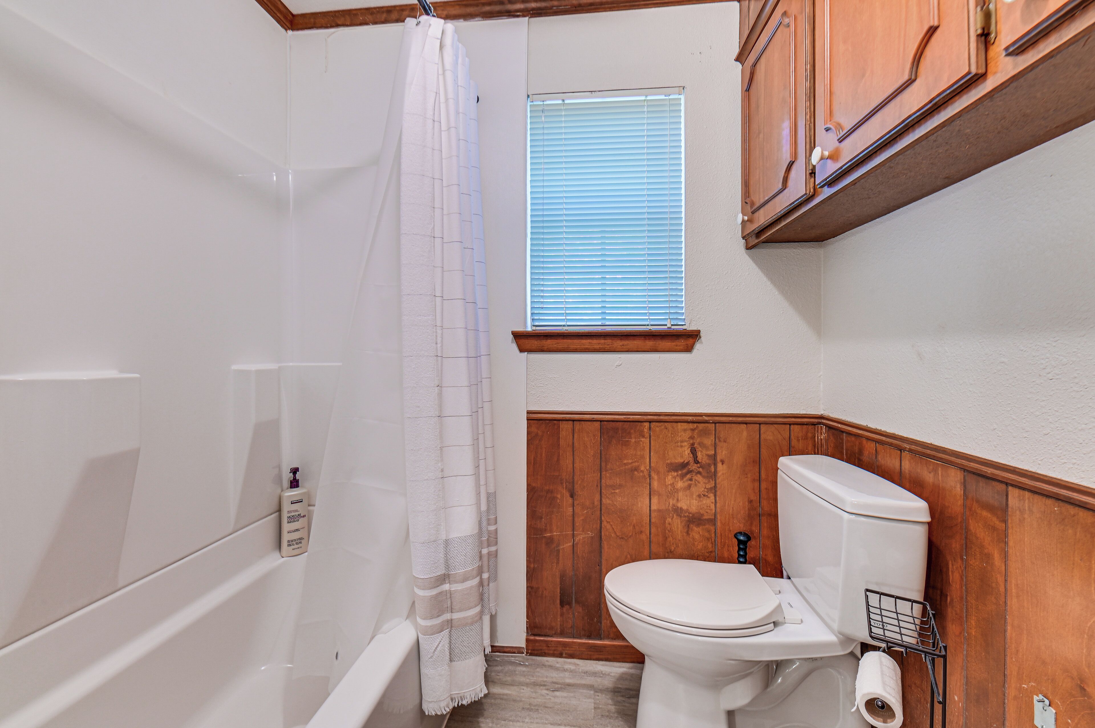A bathroom with a bathtub, toilet, and window.