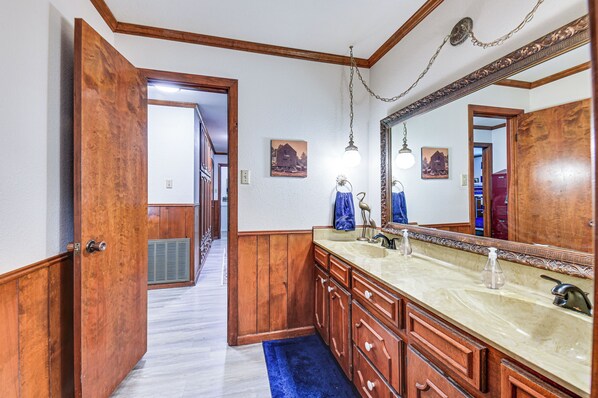 Une salle de bain avec des meubles en bois, un grand miroir et un tapis bleu.
