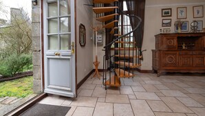 A spiral staircase in a room with a wooden cabinet and framed pictures on the wall.