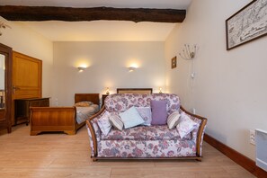 A room with a wooden floor, a floral-patterned sofa, a wooden bed, and a wooden wardrobe.