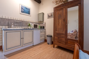 A kitchen with a wooden cabinet, a microwave, and a coffee maker.