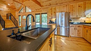 Una cocina amplia con armarios de madera, un refrigerador de acero inoxidable y un lavamanos grande.