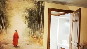 Ein Zimmer mit einem großen Gemälde einer Waldszene, einer Holztür und einem Fliesenboden.