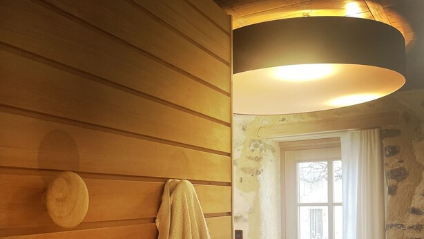 Eine Holzwand mit einem Handtuch an einem runden Knopf, eine Steinwand und eine Tür mit Fenster.