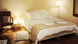 Ein Schlafzimmer mit einem Bett, einem Sessel, einer Lampe und Wanddekor.