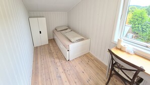 Een kleine, praktische kamer met een bed, een bureau en een raam.