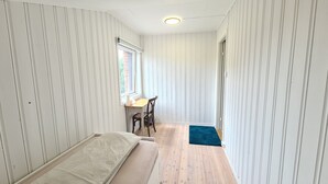 Een kleine kamer met een bed, een bureau en een stoel.
