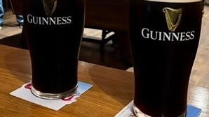 Two Guinness beer glasses on a wooden table in a room with a pool table and people playing pool. - Cortoon Inn, Family Room 1 (1DBL +2SGL) (Tuam)