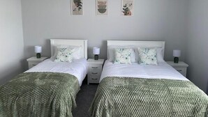 A twin bedroom with two beds, each with a white headboard, a bedside table, and a lamp. There are three framed artworks on the wall above the beds. - Cortoon Inn, Triple Room 2 (1 DBL + 1SGL) (Tuam)