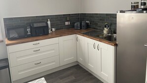 Una cocina compacta con armarios blancos, microondas, tostadora y refrigerador.