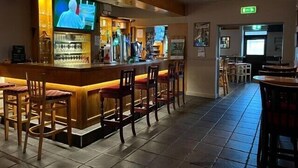 A bar area with a counter, bar stools, and a television screen.