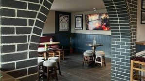 Un intérieur chaleureux avec des murs en briques, une cheminée et un coin salon équipé de tabourets et d’une table.