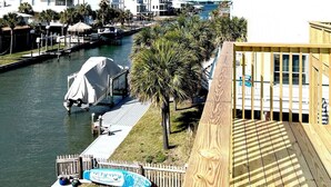 A waterfront property with a wooden deck, a covered dock, and a view of a marina with boats.
