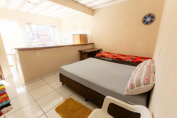 Una habitación pequeña con cama, kitchenette y ventana.