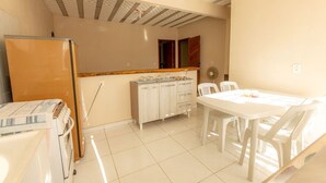 Una cocina con refrigerador, encimera de madera, armarios y un comedor con mesa y sillas.