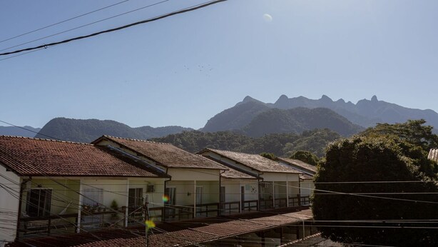 Un barrio residencial con casas de techo rojo y una cadena montañosa al fondo.
