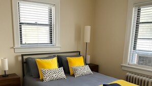 Une chambre à coucher bien rangée, avec un lit, deux tables de chevet et une lampe sur pied.