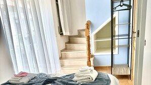 Un dormitorio con una cama, una escalera de madera y un pasillo.