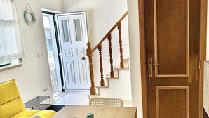 A room with a wooden table, white chairs, a yellow sofa, and a wooden door.