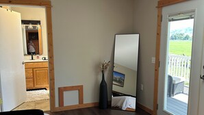 Ein Schlafzimmer mit einem großen Bett, einem Spiegel, einer Vase mit getrockneten Blumen und einer Schiebetür zu einem Außenbereich.