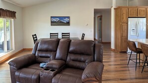 Ein geräumiges Wohnzimmer mit einer Ledersofa, einem Essbereich und einer Küche mit Holzausstattung.