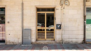 Un bâtiment doté d’une grande porte d’entrée en verre, d’un compteur et d’une petite poubelle.