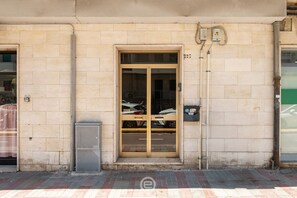 Ein Gebäude mit einem großen Glastür-Eingang, einem Stromzähler und einer kleinen Mülltonne.