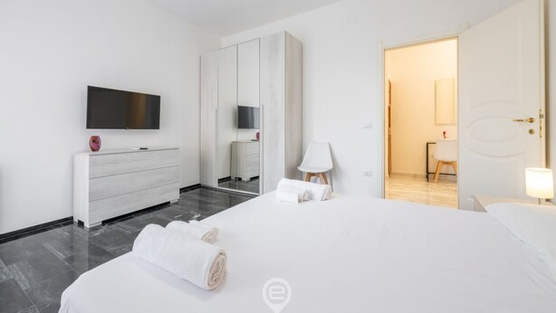 Une chambre d’hôtel moderne dotée d’un grand lit, d’un téléviseur à écran plat, d’une armoire et d’une salle de bain visible à travers une porte ouverte.
