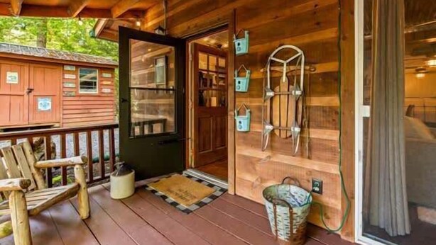 A wooden cabin with a porch, a door, and a window.