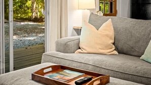 A modern living room with a grey sofa, a wooden tray table, and a remote control.