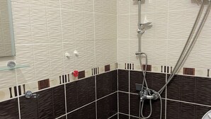 Een badkamer met douche, wastafel en toilet.