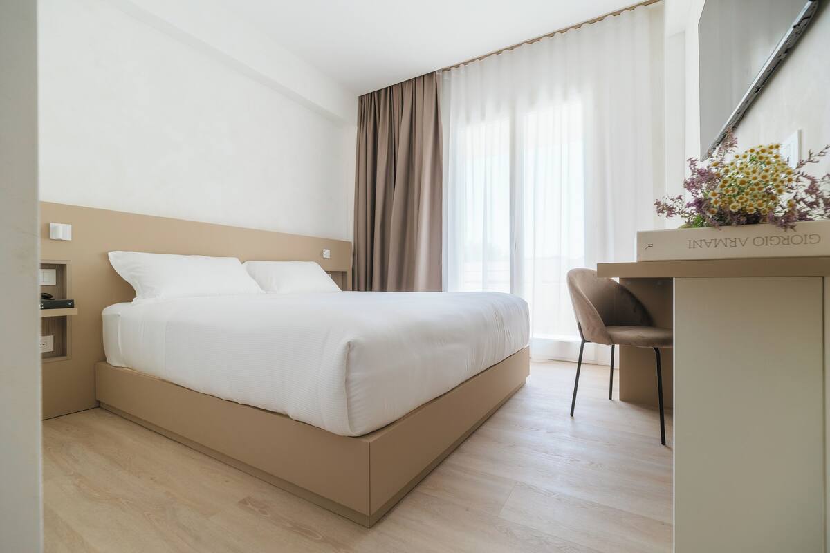 A modern hotel room with a large bed, a desk, and a chair.