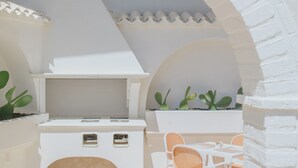 An outdoor patio with a white grill, two wicker chairs, and potted plants. - Maison Sirolo (Sirolo)