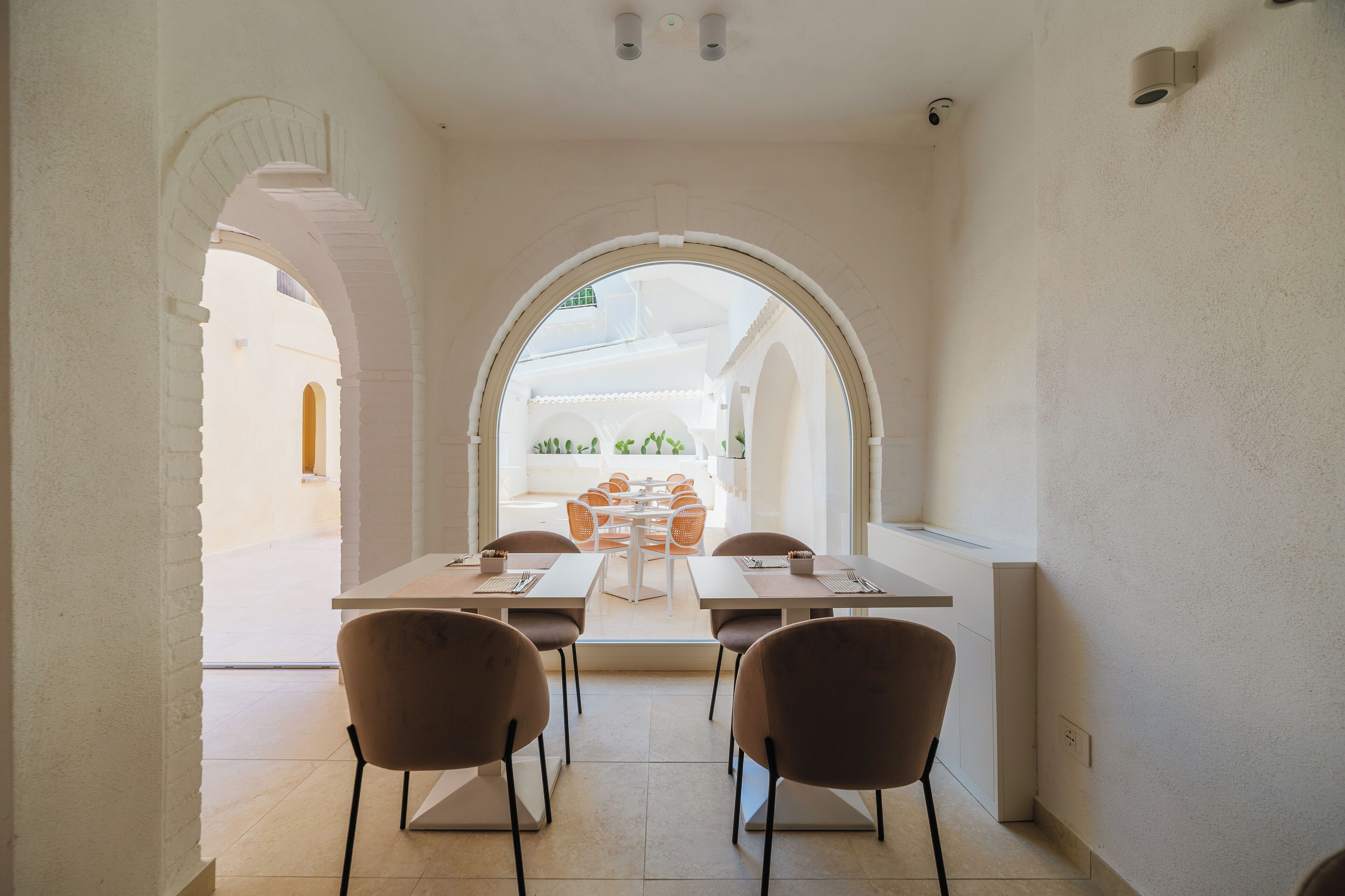 Un comedor con mesa y sillas, un arco de entrada y vistas a una zona de estar exterior.