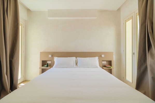A hotel room with a large bed, two bedside tables, and a nightstand. - Maison Sirolo (Sirolo)