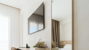 A modern hotel room with a large mirror, a desk with a chair, a bed, and a television mounted on the wall. - Maison Sirolo (Sirolo)