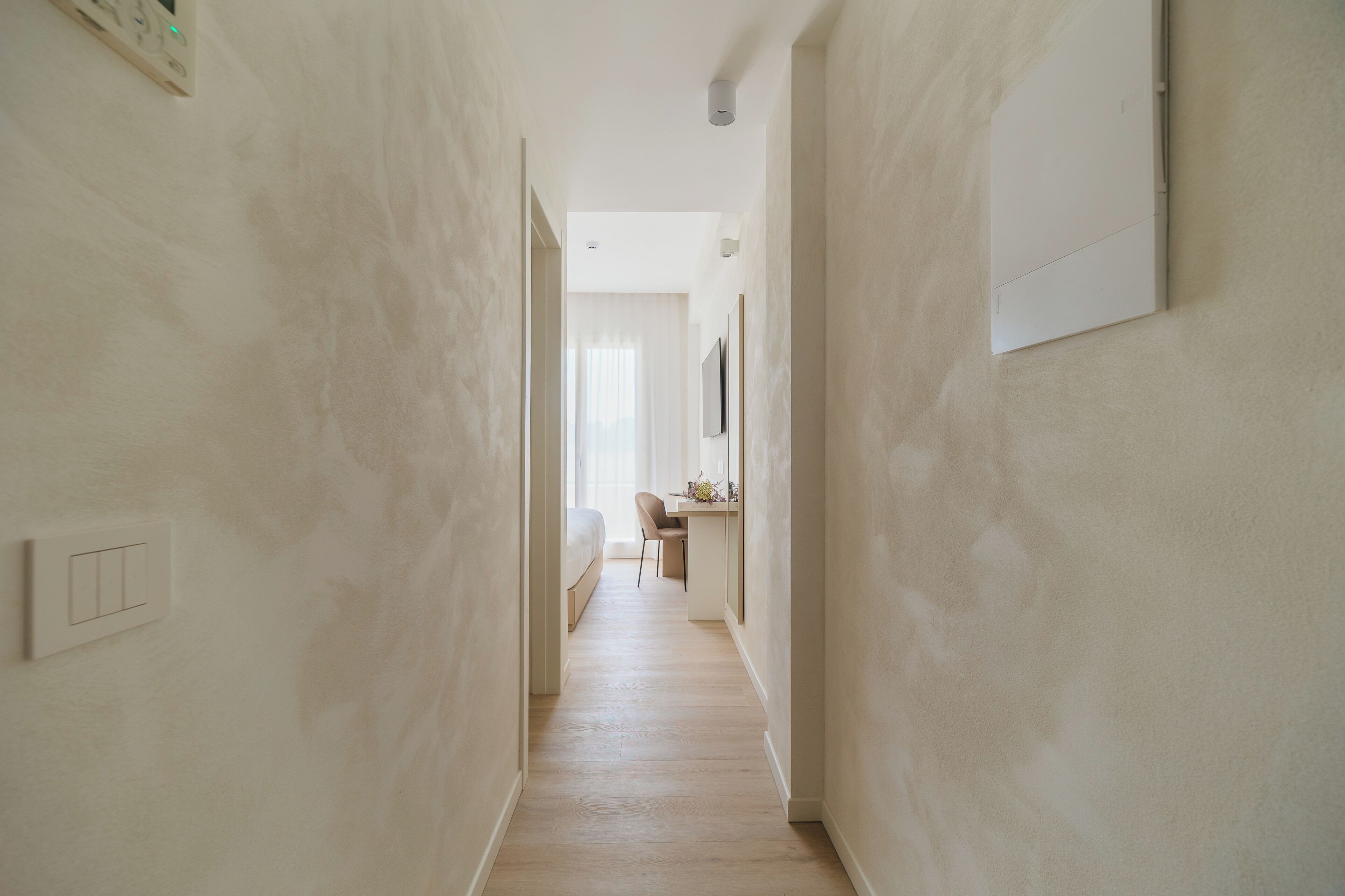 A narrow hallway with a bed and a desk at the end.