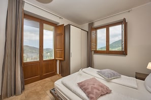 A bedroom with a bed, a window, a wardrobe, and a view of the outdoors.