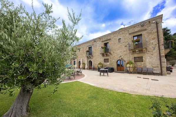 A stone building with outdoor seating, a tree, and a clear sky.