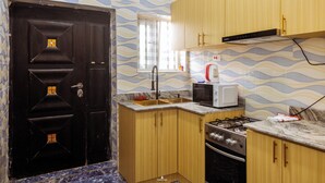 Una cocina con armarios de madera, una puerta negra, una ventana, un microondas y una estufa a gas.